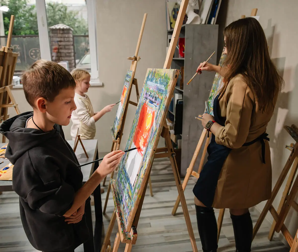 Children and teacher painting on easels